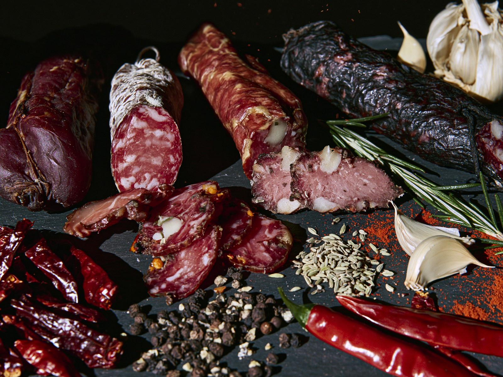 An assortment of cured meats with garlic, rosemary, and spices