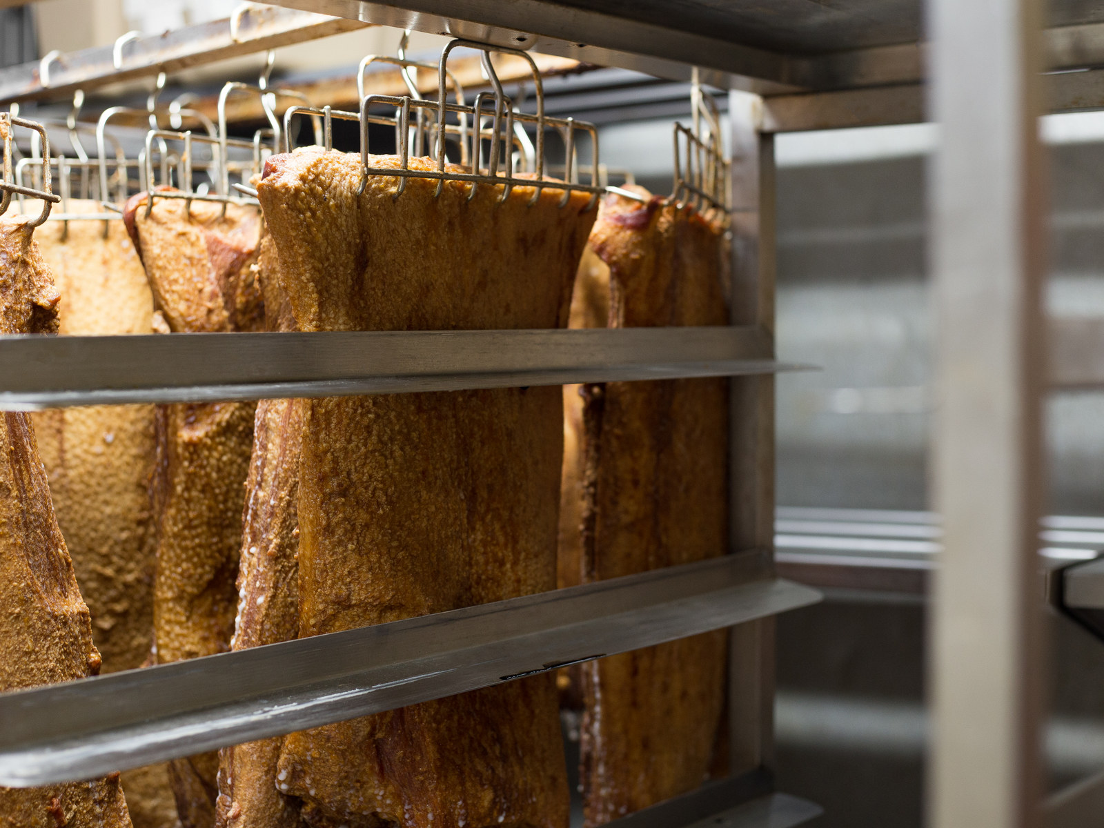 Smoked products hanging on stainless-steel racks