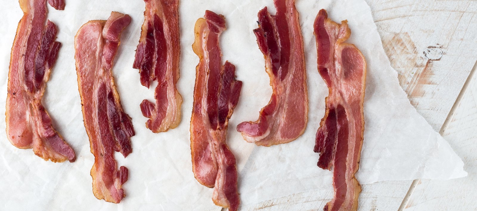 Slices of black pepper bacon arranged on parchment